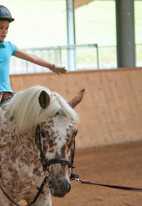 Kind reitet ein Pony in der hoteleigenen Reithalle des Familienhotels Schreinerhof